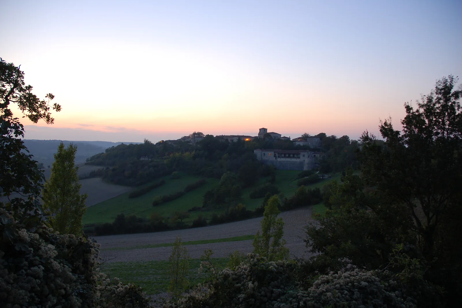 Il borgo arroccato di Pujols sopra i campi, al tramonto